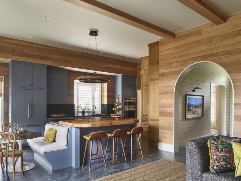 Open-plan kitchen and living area with blue cabinetry, butcher block island, and cedar shiplap walls designed by Amity Worrel & Co. — aging-in-place interior design in Austin, TX