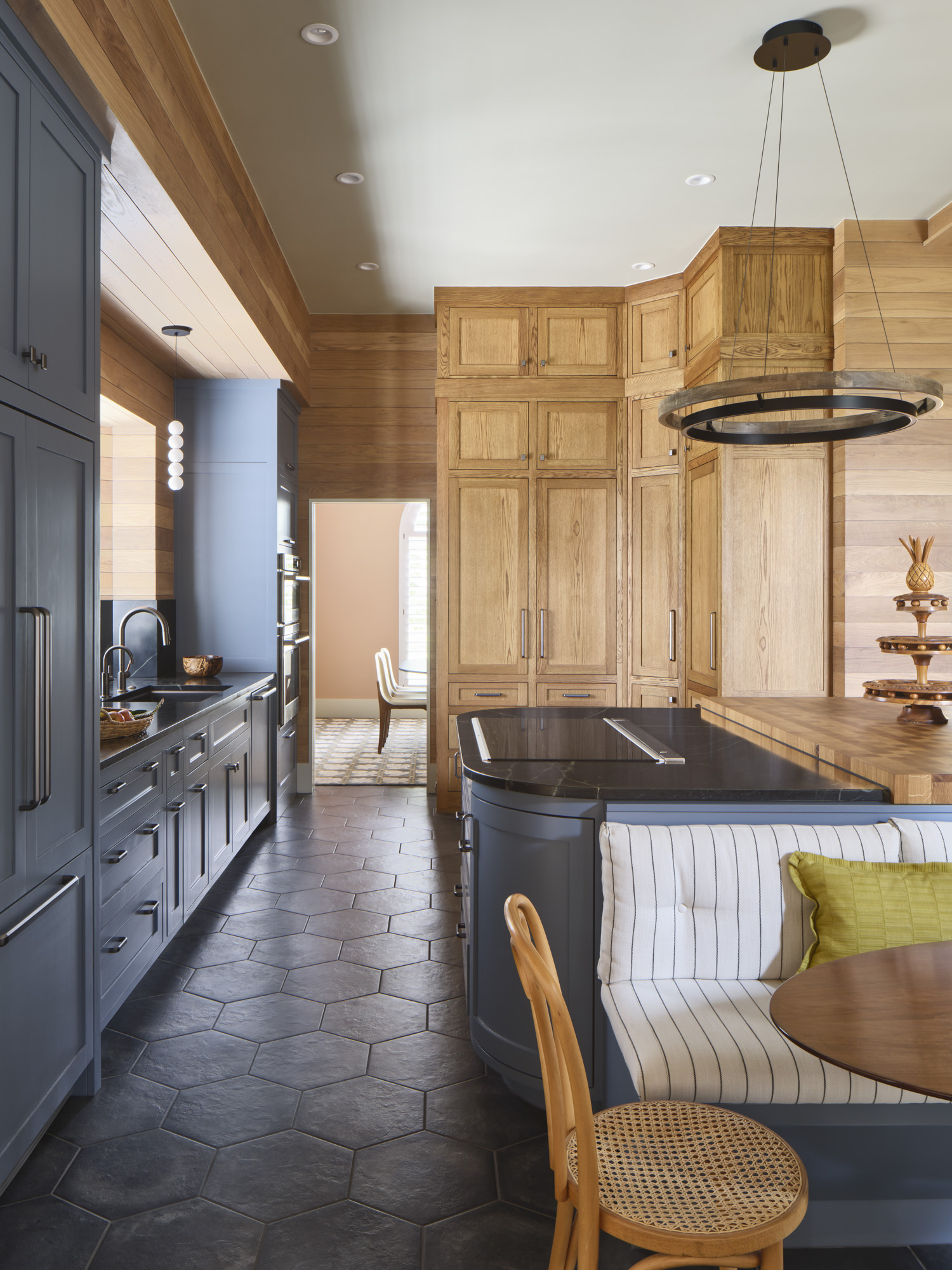 Detailed kitchen with blue-gray cabinetry, natural wood pantry, hexagonal tile floors, and built-in banquette designed by Amity Worrel & Co. — aging-in-place kitchen remodeling in Austin, TX