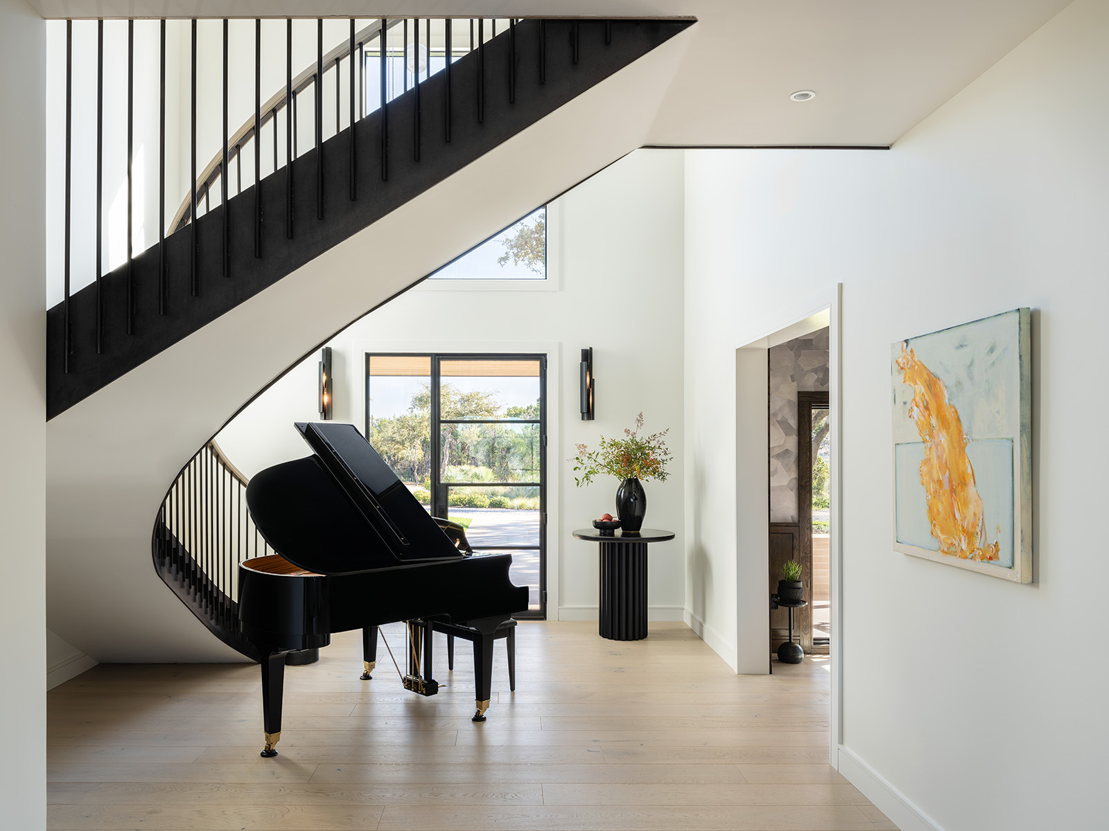 Elegant home foyer with curved staircase and grand piano built by Texas Construction Company — aging-in-place remodeling contractor in Austin, TX