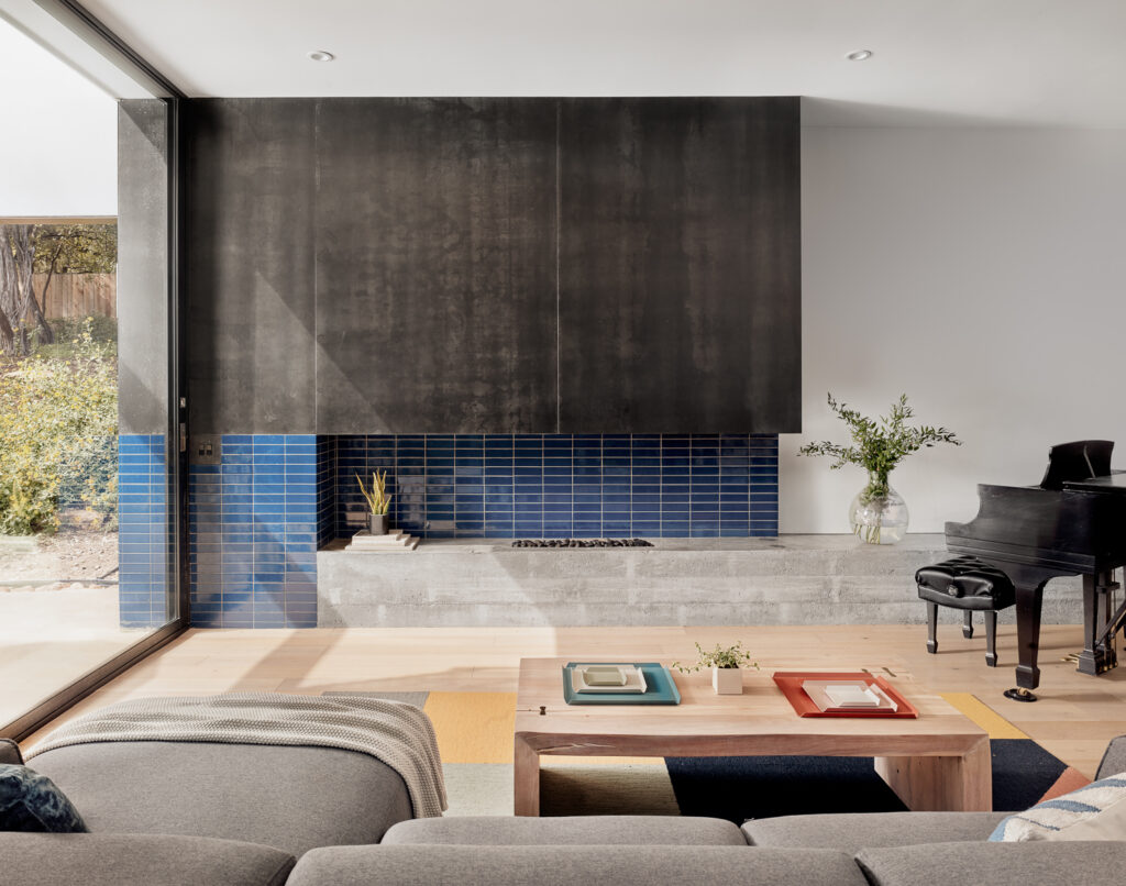 Open-plan living room with steel fireplace surround and blue tile by Texas Construction Company — aging-in-place home remodeling in Austin, TX